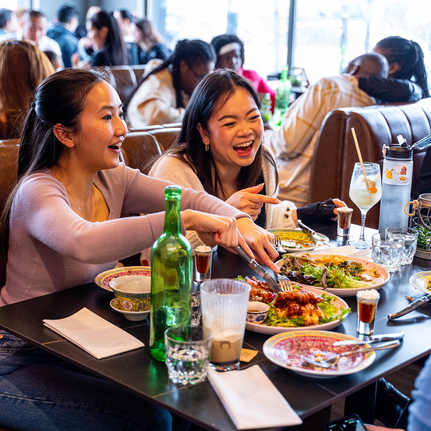 Amies qui rient en partageant un brunch dans une salle animée